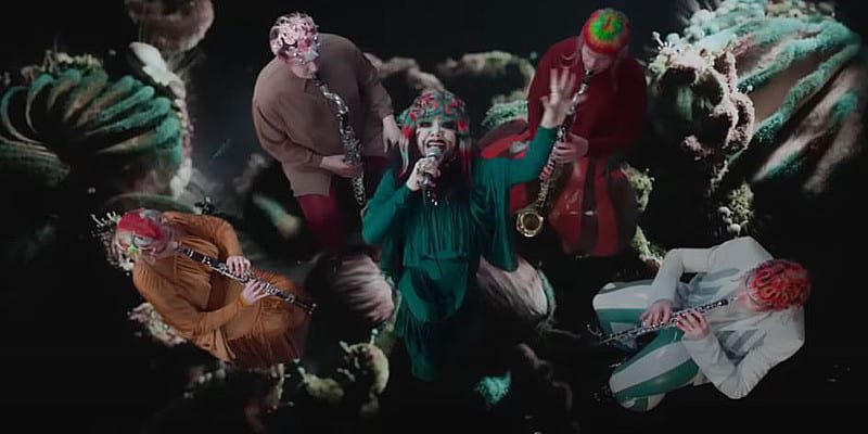 Björk umringt von Musikern in bunter Kleidung